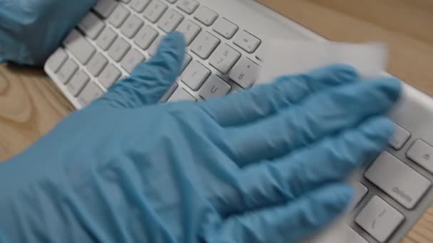 Человек в защитных перчатках очищает клавиатуру спиртовым дезинфицирующим средством и удаляет грязь влажной салфеткой. Профилактические мероприятия в период вспышки коронавируса. Закрывай. Медленное движение. — стоковое видео