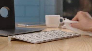 Bir kadın klavyenin yüzeyine antiseptik sıkar ve onu tehlikeli virüslerden, mikroplardan ve bakterilerden peçeteyle temizler. Eller yukarı. Yavaş çekim.