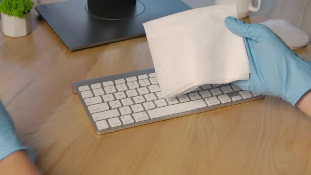 Les mains dans les gants de protection pulvérisent un antiseptique sur une serviette et nettoient soigneusement la surface du clavier contre les virus, les germes et les bactéries dangereux. Ferme là. Mouvement lent. — Video