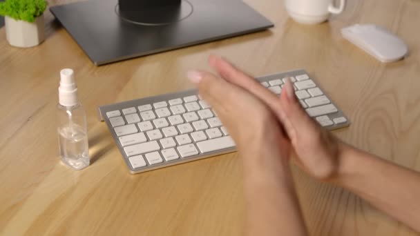 Een vrouw behandelt haar handen met een ontsmettingsmiddel en typt op een toetsenbord. Thuis werken op afstand. Voorzorgsmaatregelen voor de epidemie van het virus. Handen dicht. Langzame beweging. — Stockvideo