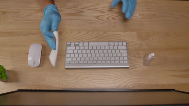 Un uomo spruzza disinfettante su un tovagliolo e pulisce una tastiera del computer in un ufficio o in casa durante la quarantena. Igiene sul posto di lavoro per prevenire l'infezione virale. Avvicinamento delle mani ai guanti. Rallentatore. — Video Stock