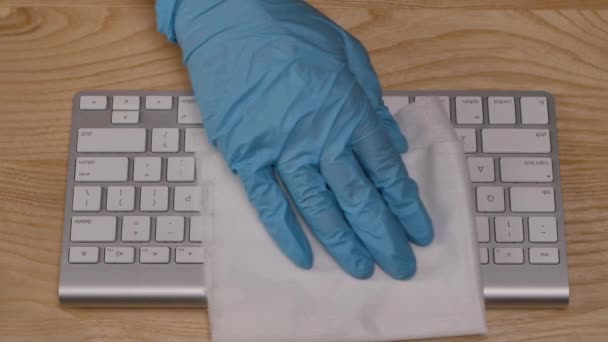 Las manos en guantes azules protectores rocían un antiséptico sobre una servilleta y limpian a fondo la superficie del teclado de virus, gérmenes y bacterias peligrosos. De cerca. Movimiento lento. — Vídeos de Stock