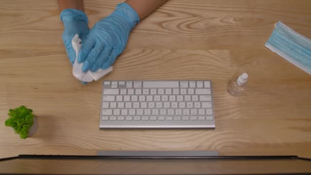 Biznes w rękawiczkach ochronnych dezynfekuje mysz komputerową środkiem antyseptycznym i pisze na klawiaturze komputera. Widok z góry. Zamknij drzwi. Zwolniony ruch. — Wideo stockowe