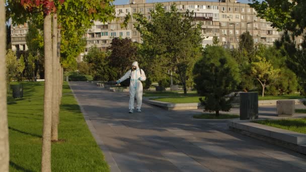 El virólogo en equipo de protección desinfecta superficies en un parque en cuarentena contra el coronavirus covid-19 con un desinfectante antibacteriano. Movimiento lento. — Vídeos de Stock