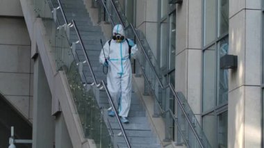 Basınçlı çamaşır makinesiyle sokakları temizlemek. Bir hademe umumi bir yerde merdivenleri ve tırabzanları dezenfekte eder. Karantinaya alınmış anti-bakteriyel önlemler. Yavaş çekim.