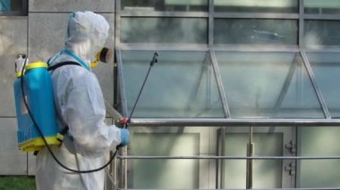 Koruyucu giysili ve solunum cihazlı işçiler koronavirüsteki korkuluklara kimyasal spreyler sıkarlar. Ağır çekim. Kapat..