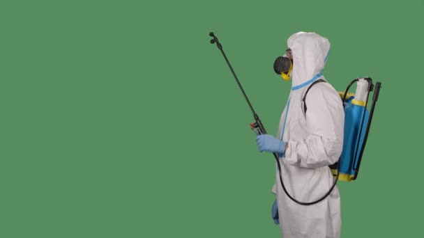 Virológus védő egyenruhában sétál, és fertőtleníti a területet egy nagy nyomású mosó egy zöld képernyőn, chroma gombot. Coronavirus prevenciós koncepció. Lassú mozgás. Közelről.. — Stock videók