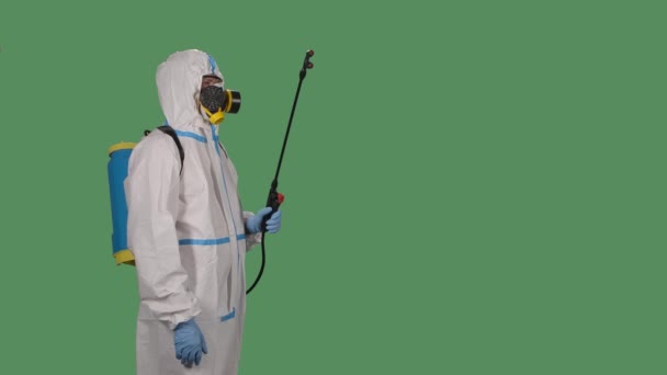 Vista laterale disinfezione uomo con speciale suite bianca e un respiratore spray soluzione antisettica su uno schermo verde, chiave cromatica. Al rallentatore. Da vicino.. — Video Stock