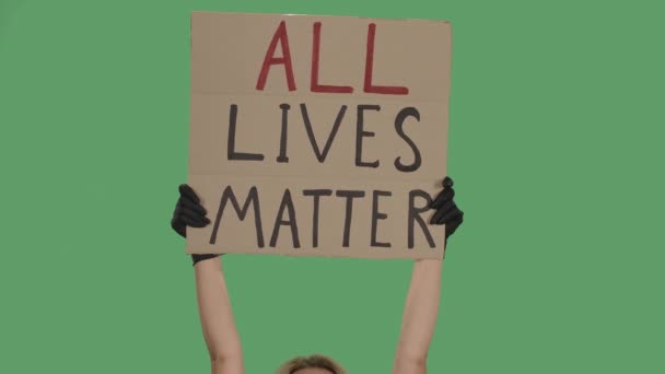 Die Hände eines Unbekannten in schwarzen Handschuhen heben ein Pappposter ALL LIVES MATTER. Gleichheit und Einheit. Isoliert ein grüner Bildschirm, Chroma-Taste. Aus nächster Nähe. Zeitlupe. — Stockvideo