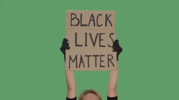 BLACK LIVES MATTER. Protest text message on cardboard. Stop racism. Police violence. Banner design concept. Hands holding a poster a green screen, chroma key. Close up. Slow motion. — Stock Video