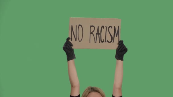 Руки невідомої людини в чорних рукавичках піднімають картонний плакат NO RACISM. Багатогранність насильства та античорного расизму. Ізольований зелений екран, ключ хроми. Близько. Повільний рух . — стокове відео