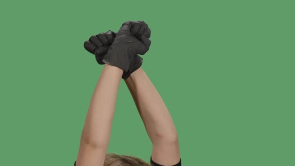 La chica rubia levanta dos manos apretadas en un puño. Símbolo de solidaridad, apoyo, saludo para expresar unidad, fuerza. Pantalla verde, croma key. De cerca. Movimiento lento. — Vídeo de stock