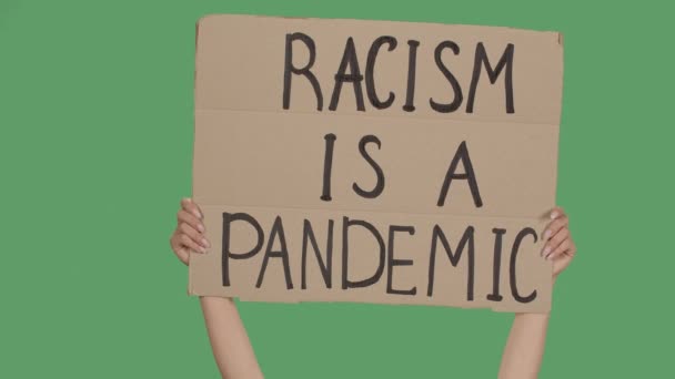 RACISM is een PANDEMIC. Protest sms op karton. Stop racisme. Politie geweld. Banner ontwerp concept. Handen met een poster, een groen scherm, chroma sleutel. Sluit maar af. Langzame beweging. — Stockvideo