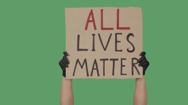 Siyah eldivenli kadın eller karton bir kutudan "Tüm Yaşamlar Önemlidir" yazan bir poster alıyor. Eşitlik ve birlik için savaş. Yeşil ekran, krom anahtar. Kapatın. Yavaş çekim. — Stok video