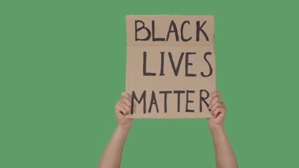 As mãos femininas mantêm um cartaz de uma caixa de papelão com as palavras BLACK LIVES MATTER. Protesto contra o racismo e a brutalidade policial. Isolado uma tela verde, chave chroma. Fecha. Movimento lento. — Vídeo de Stock