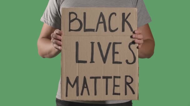 Muž před sebou drží plakát z lepenkové krabice se slovy BLACK LIVES MATTER. Koncept stávky a antirasismu. Izoloval zelenou obrazovku, chromatický klíč. Zavřít. Zpomalený pohyb. — Stock video