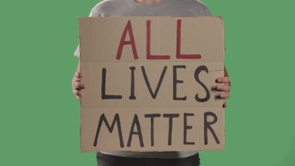 L'uomo tiene davanti a sé un poster da una scatola di cartone con la scritta ALL LIVES MATTER. Concetto di sciopero e antirazzismo. Isolato uno schermo verde, chiave cromatica. Chiudete. Rallentatore. — Video Stock