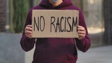 Erkek protestocuların elindeki karton posterde RACISM yok. Poster ve elin yakın çekimi. Irkçılık yapma, ırkçılık yapma. Şehir sokak protestosu. Yavaş çekim.