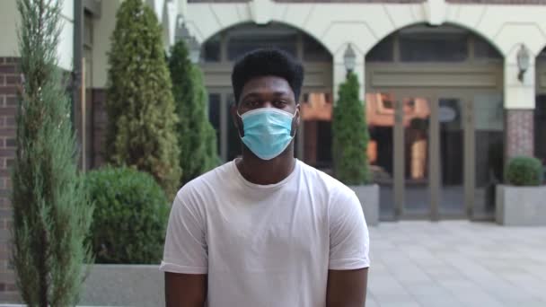 Portret van een jonge Afro-Amerikaanse man met een beschermend medisch masker die naar de camera kijkt. Concept voor de bescherming van de gezondheid van Corona virus. Langzame beweging. Sluiten.. — Stockvideo