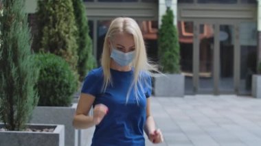Çekici bir genç kadının portresi kameraya bakıyor koruyucu bir tıbbi maske takıyor ve sonra onu çıkarıyor. Corona virüsü sağlık koruma konsepti. Ağır çekim. Kapat..