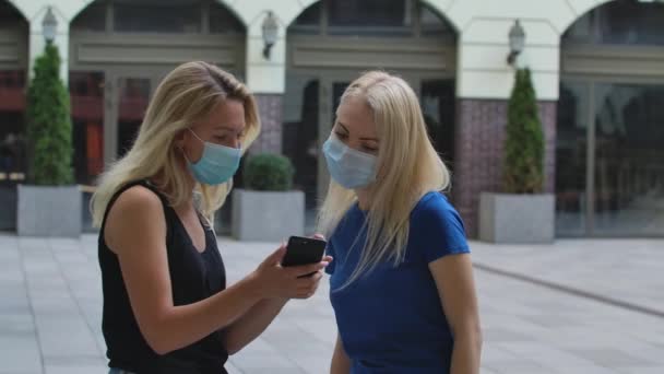 Güzel bir sarışın, sokakta tanıştığı bir kadına akıllı telefonu göstererek doğru yere nasıl gidileceğini öğrenir. Corona virüsü sağlık koruma konsepti. Ağır çekim. Kapat.. — Stok video