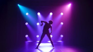 Siyahlar içinde profesyonel bir balerin. Dinamik spot ışıkları altında zarif bir şekilde bale yapıyor ve sahnede sigara içiyor. Güzel, ince bir siluetin silueti.