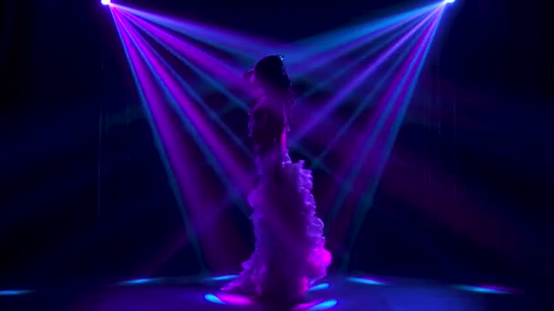 Bauchtänzerin im weißen orientalischen Kostüm schüttelt die Hüften. Gedreht in einem dunklen Studio mit Rauch und Neonlicht. Silhouetten. Zeitlupe. — Stockvideo