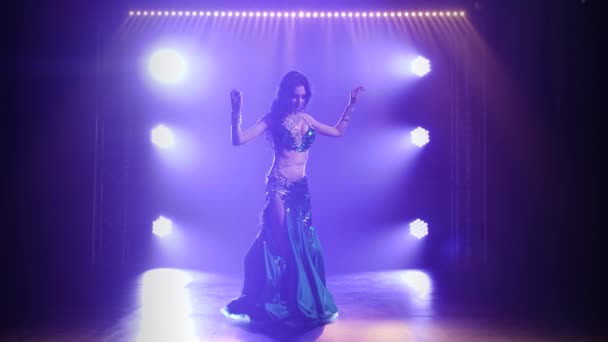 Arabská břišní tanečnice v exotickém tance. Natočeno v tmavém studiu s kouřem a neonovým osvětlením. Siluety štíhlého pružného těla. Zpomalený pohyb. — Stock video