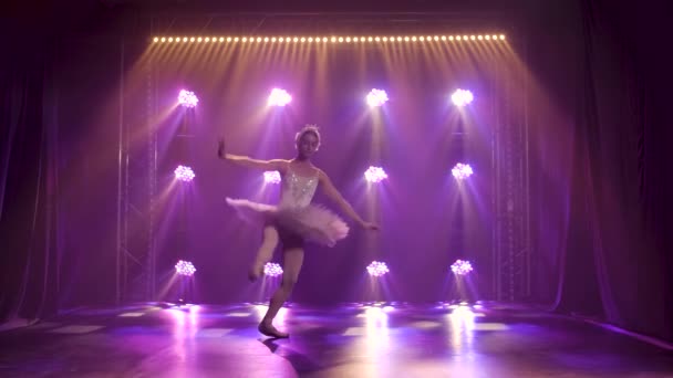 Klassieke ballet choreografie doordrenkt door jonge mooie sierlijke ballerina in witte tutu. Witte zwaan rol in de uitvoering van vrouwelijke kunstenaar. Opgenomen in een duisternis op schijnwerpers achtergrond van studio. — Stockvideo
