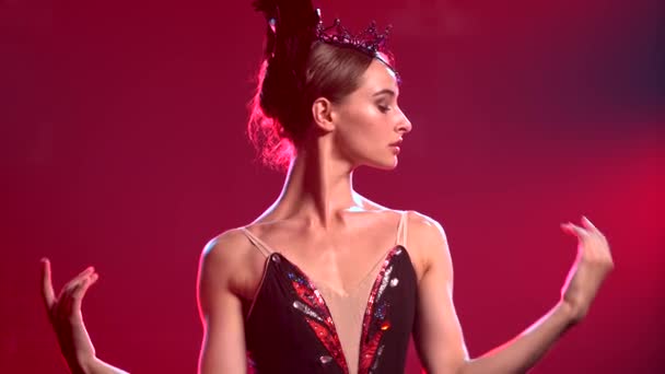 Půvabná baletka v elegantním obrazu černé labutě. Perfektní pas s rukama. Natočeno v tmavém studiu s kouřem a červeným neonovým osvětlením. Zavřít. — Stock video