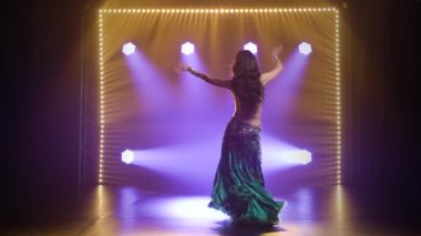 Egzotik dansında Arap dansçı. Duman ve neon ışıkla karanlık bir stüdyoda çekildi. Yavaş çekim.