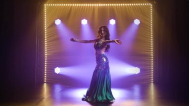 Egzotik dansında Arap dansçı. Duman ve neon ışıkla karanlık bir stüdyoda çekildi. Yavaş çekim.