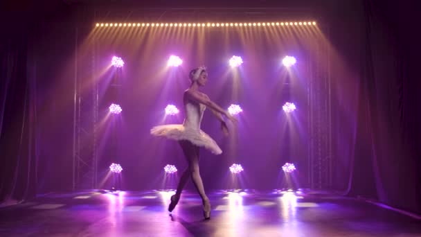 Půvabná baletka tančící bílou labutí část. Tanec prvků klasického baletu. Natočeno v tmavém studiu s kouřem a neonovým osvětlením. Zpomalený pohyb. — Stock video