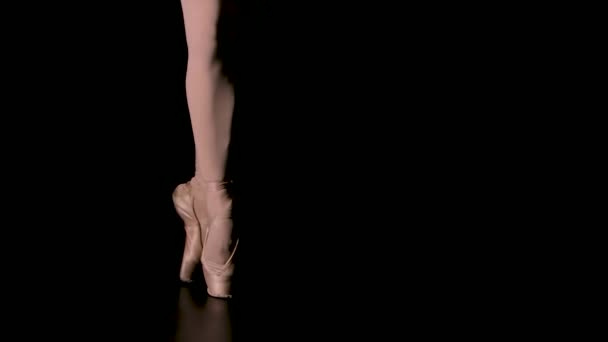 Gambe aggraziate di una ballerina in scarpe da punta bianche. La ballerina mostra ballerine classiche. Girato in un'oscurità su sfondo riflettori di studio. Chiudete. Rallentatore. — Video Stock