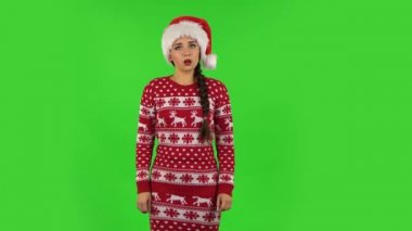 Noel Baba şapkalı tatlı kız gücenmiş ve gülümsüyor. Yeşil Ekran