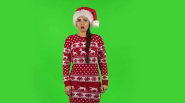 Noel Baba şapkalı tatlı kız çok alıngan ve başka tarafa bakıyor. Yeşil Ekran
