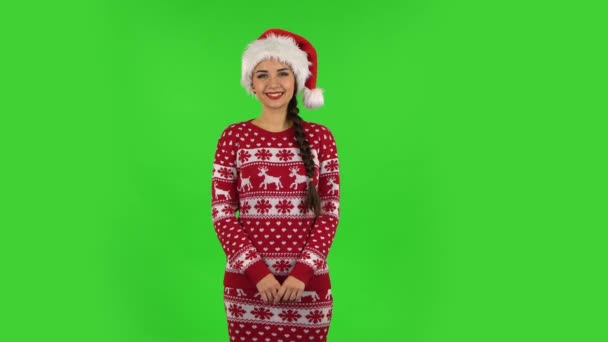 Милая девочка в шляпе Санта Клауса улыбается, глядя в камеру. Зеленый экран — стоковое видео