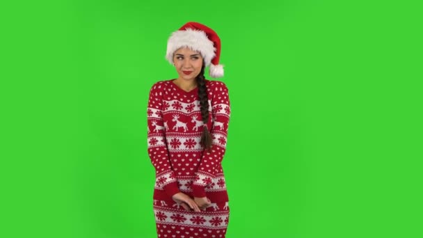 Sweety girl in Santa Claus hat is coquettishly smiling while looking at camera. Green screen — Stock Video