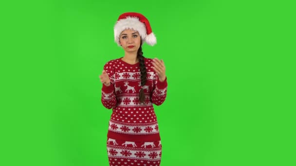Słodziutka dziewczyna w kapeluszu Świętego Mikołaja klaska w dłonie obojętne. Zielony ekran — Wideo stockowe