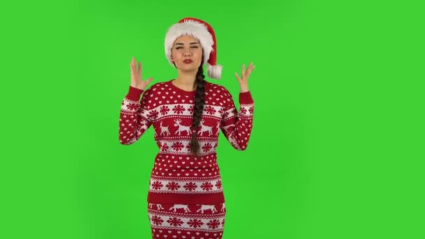 サンタクロースの帽子の甘い女の子が話していると何かのための側の手を指している、スペースをコピーします。緑の画面 — ストック動画