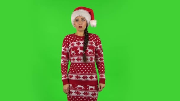 Słodka dziewczyna w kapeluszu Świętego Mikołaja jest bardzo obrażona i odwraca wzrok. Zielony ekran — Wideo stockowe