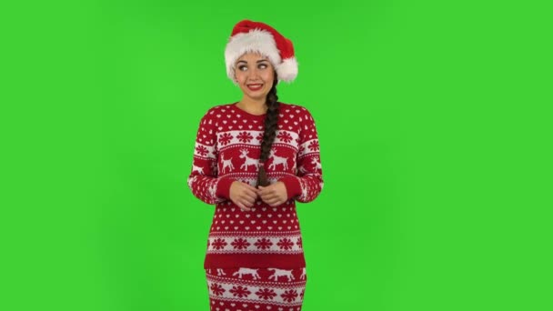 Мила дівчина у капелюсі Санта Клауса виражає свою невинність. Зелений екран — стокове відео