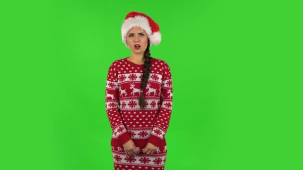Милая девочка в шляпе Санта Клауса сердито указывает на себя, говоря, кто я нет спасибо мне не нужно. Зеленый экран — стоковое видео