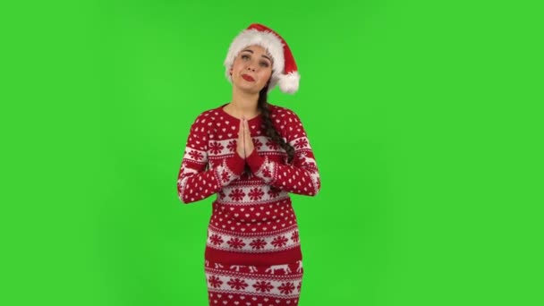Sweety Mädchen mit Nikolausmütze hält Palme zusammen und fragt nach etwas. Grüner Bildschirm — Stockvideo