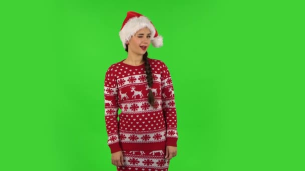 Dolce ragazza in cappello Babbo Natale è sorridente ampiamente e ammiccante. Schermo verde — Video Stock