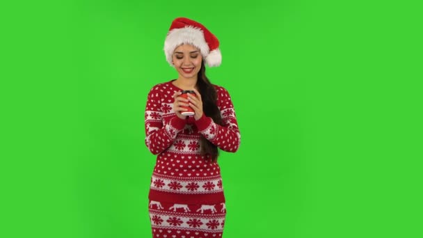 Милая девочка в шляпе Санта Клауса наслаждается кофе. Зеленый экран — стоковое видео
