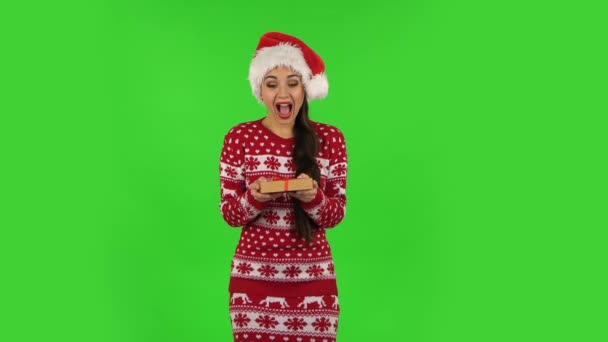 サンタクロースの帽子の甘い女の子は贈り物と喜びを開いています。緑の画面 — ストック動画