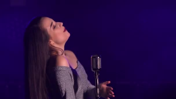 Side view of young professional female singer. Face of a beautiful girl performing song on stage into the microphone. Musical concert. — Stock Video