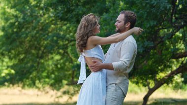 Bir çift, yemyeşil bir ormanda romantizmi ve doğadaki bağlantıyı simgeleyen sevgi dolu bir kucaklaşmayı paylaşıyor..