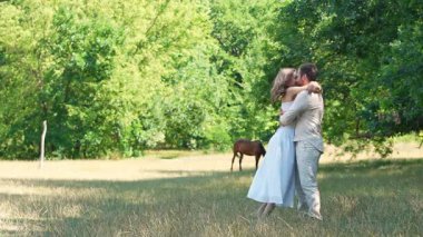 Bereketli yeşilliklerle çevrili sakin bir çayırda bir çift sevgi dolu bir kucaklaşmayı paylaşıyor..